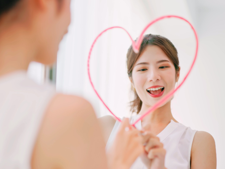 Woman making a heart on a mirror for proper self love